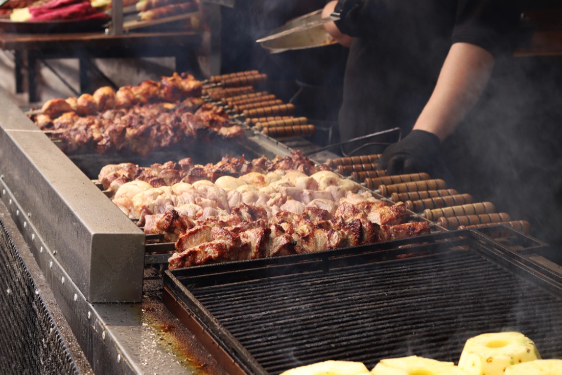 Brochetas de carne asándose en una parrilla de brasas
